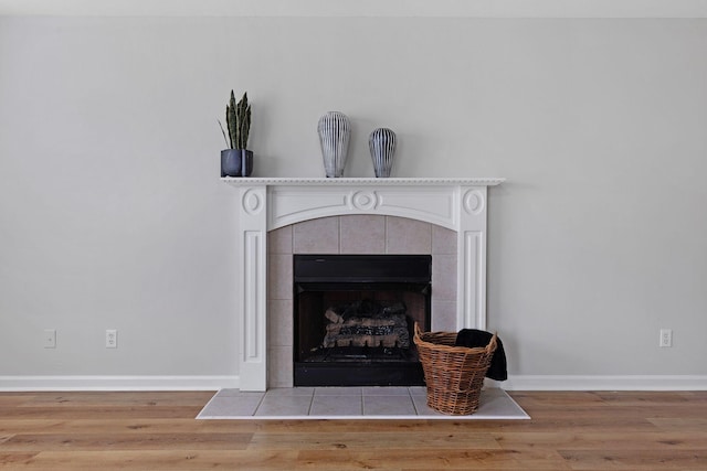 interior details featuring a tile fireplace and wood-type flooring