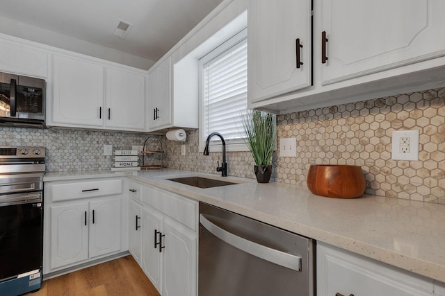 kitchen with appliances with stainless steel finishes, white cabinets, backsplash, and sink