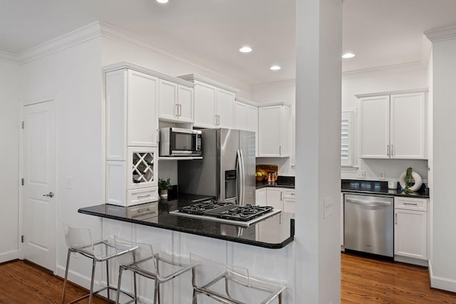 kitchen with dark wood-type flooring, appliances with stainless steel finishes, a breakfast bar, and white cabinetry