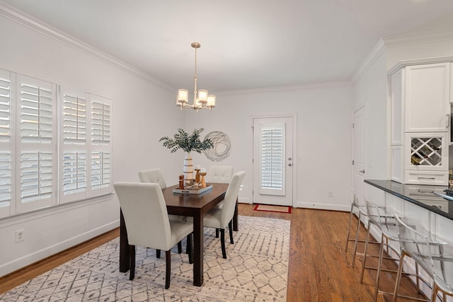 dining space with an inviting chandelier, crown molding, and light hardwood / wood-style flooring