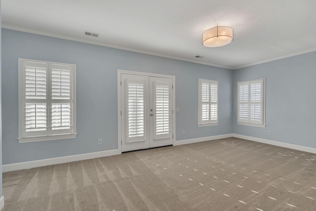 empty room featuring light colored carpet, french doors, and crown molding