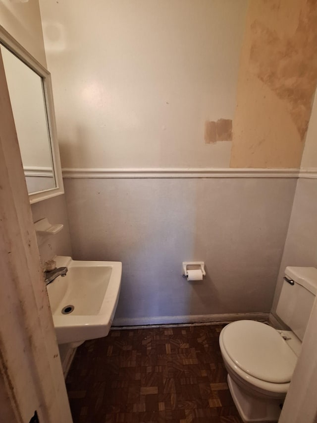 bathroom featuring toilet, sink, and parquet floors