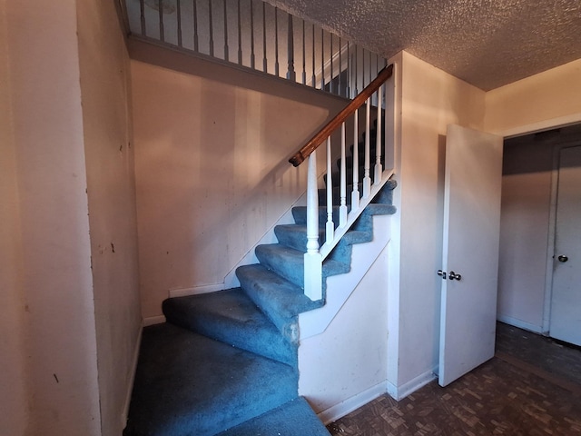 stairs featuring a textured ceiling