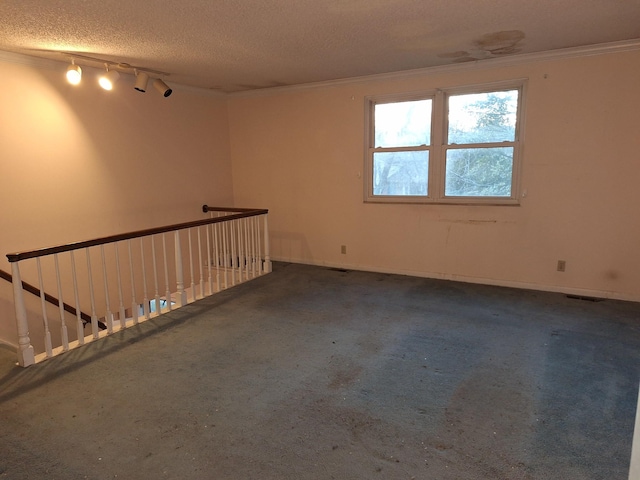 spare room featuring rail lighting, a textured ceiling, and crown molding