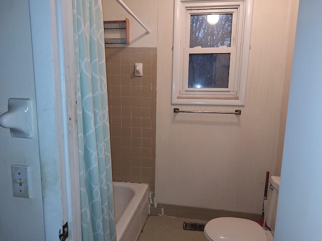 bathroom featuring shower / bath combo with shower curtain, toilet, and tile patterned flooring