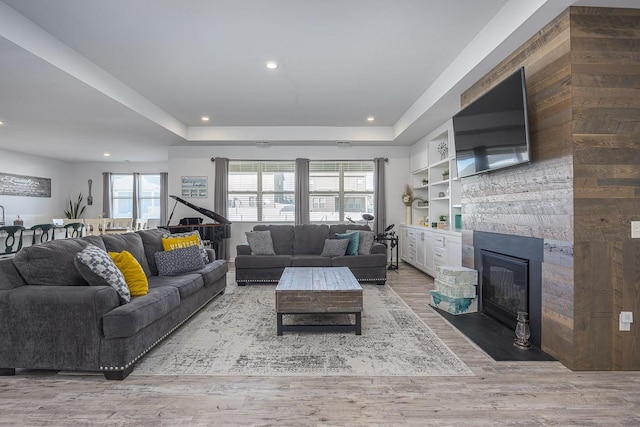 living room with a raised ceiling, built in features, and hardwood / wood-style flooring