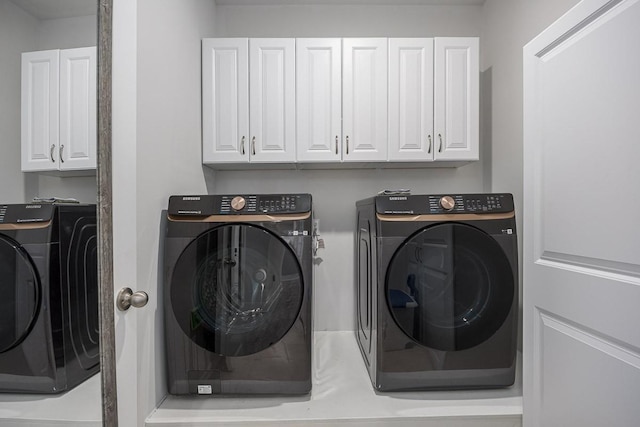 washroom featuring washer and clothes dryer and cabinets