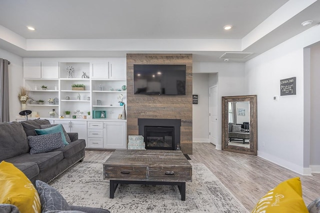 living room with light wood-type flooring and a large fireplace