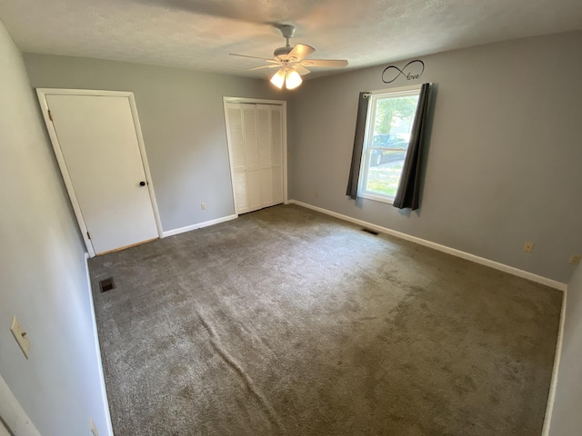 unfurnished bedroom featuring a textured ceiling, ceiling fan, and dark colored carpet