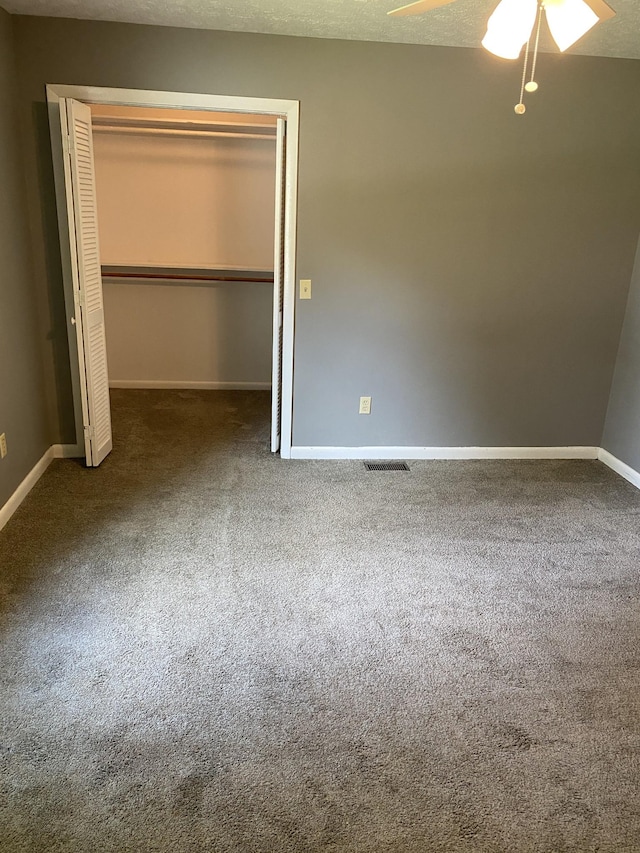 unfurnished bedroom with a textured ceiling, a closet, carpet, and ceiling fan