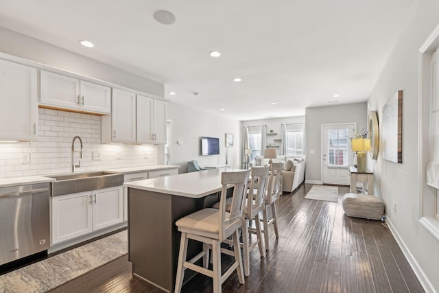 kitchen with white cabinetry, dishwasher, a kitchen island, and sink