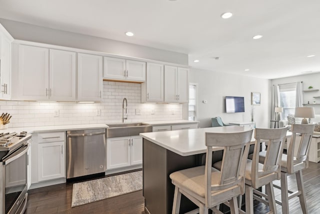 kitchen with white cabinetry, appliances with stainless steel finishes, tasteful backsplash, dark wood-type flooring, and sink