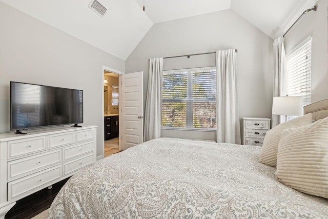 bedroom featuring multiple windows, connected bathroom, and vaulted ceiling