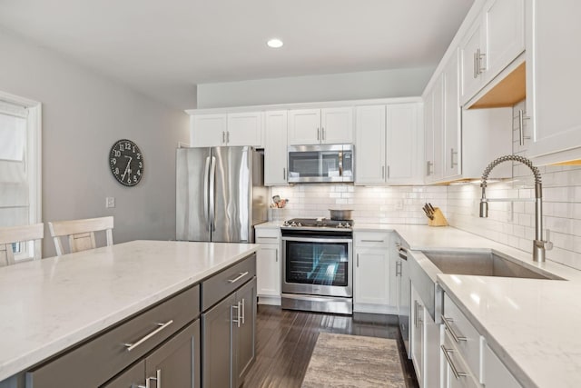 kitchen with white cabinets, backsplash, light stone countertops, and stainless steel appliances