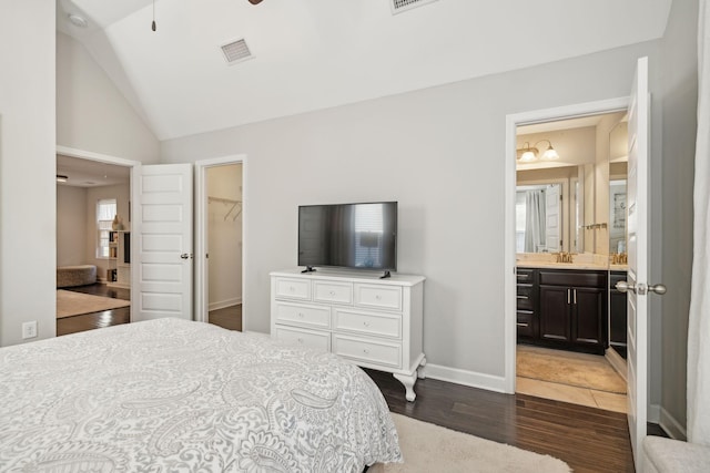 bedroom featuring ensuite bathroom, sink, dark wood-type flooring, a walk in closet, and a closet