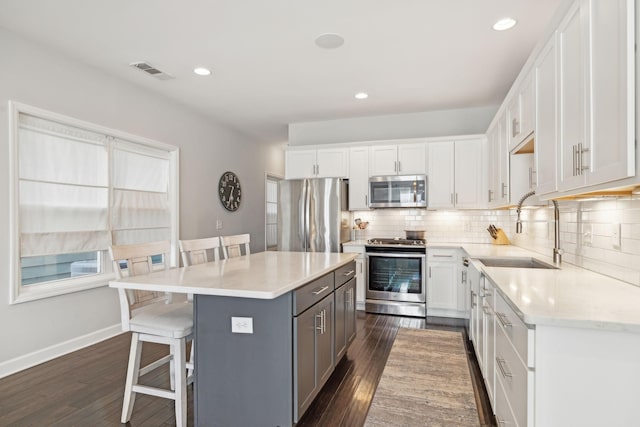 kitchen with a kitchen bar, sink, white cabinets, and stainless steel appliances