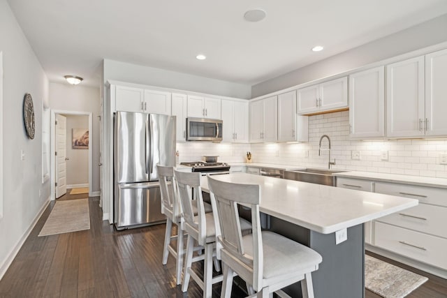 kitchen with white cabinets, sink, stainless steel appliances, and a kitchen island