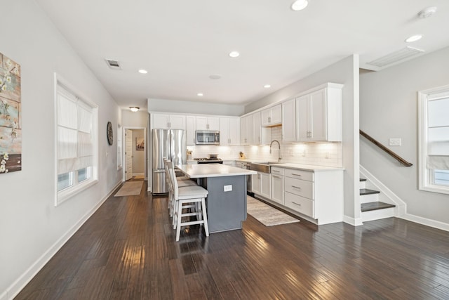 kitchen featuring white cabinetry, a breakfast bar area, appliances with stainless steel finishes, a center island, and sink