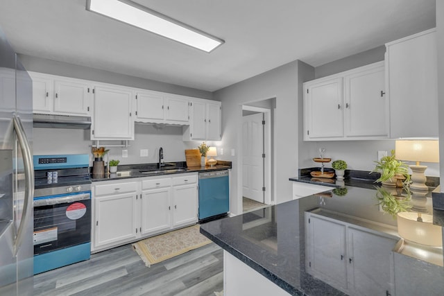 kitchen with dark stone countertops, light hardwood / wood-style floors, sink, white cabinetry, and appliances with stainless steel finishes