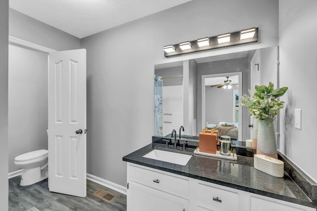 bathroom featuring a textured ceiling, wood-type flooring, vanity, toilet, and ceiling fan