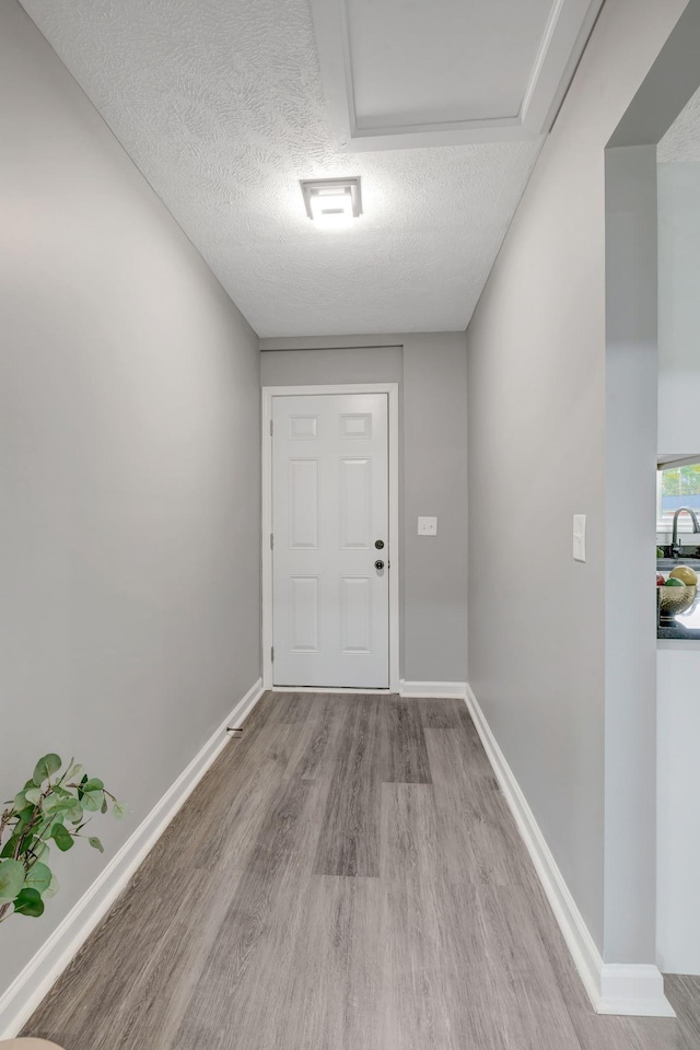 doorway featuring sink, a textured ceiling, and light wood-type flooring