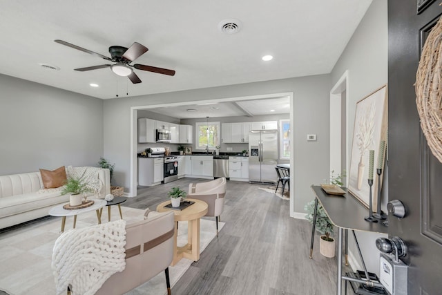 living room with ceiling fan, light hardwood / wood-style floors, and sink