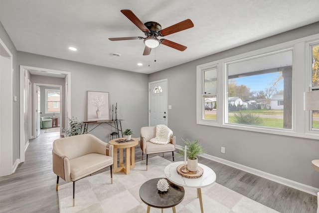 living area with ceiling fan and light wood-type flooring