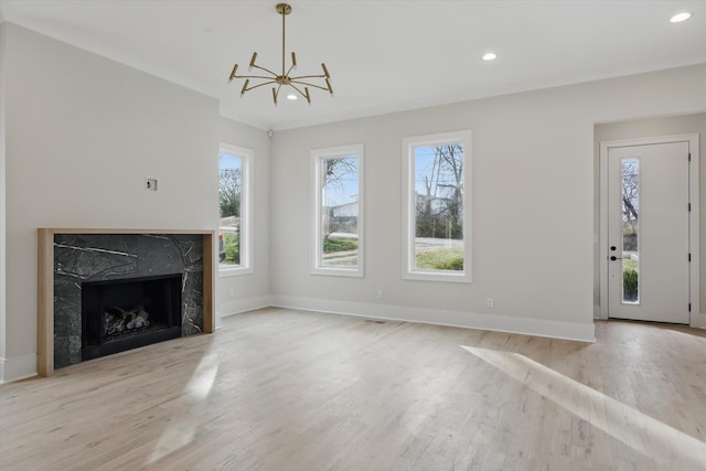 unfurnished living room featuring recessed lighting, a premium fireplace, baseboards, and wood finished floors