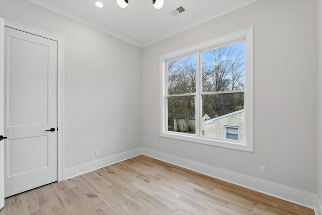 spare room with crown molding, light wood-style flooring, visible vents, and baseboards