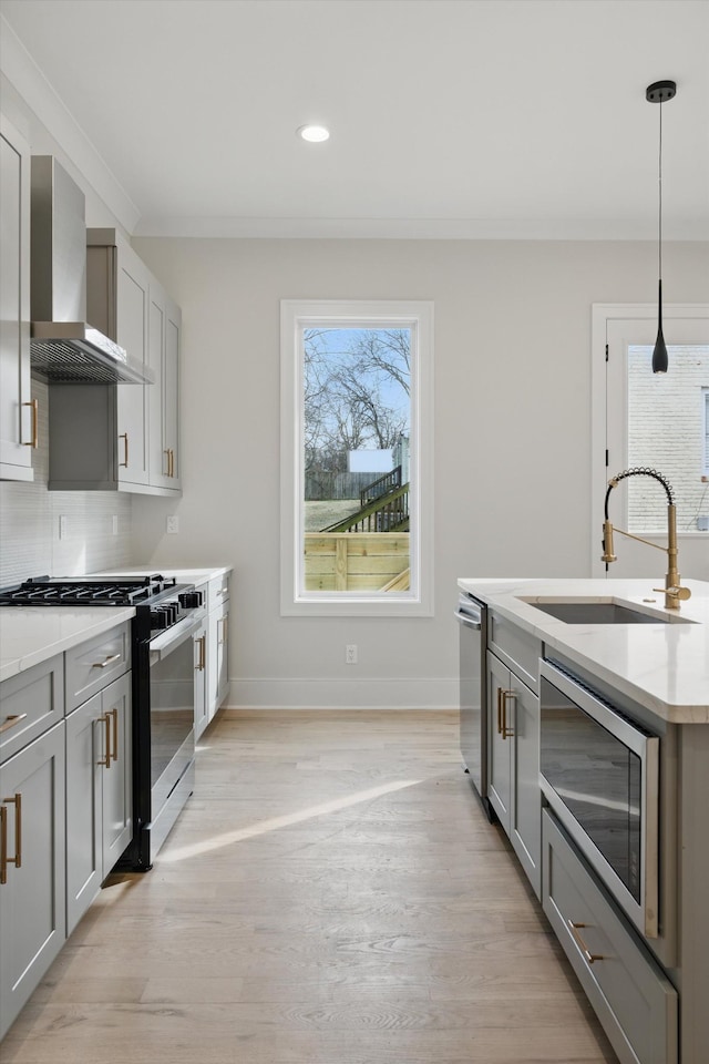 kitchen with backsplash, gray cabinetry, wall chimney range hood, stainless steel appliances, and a sink