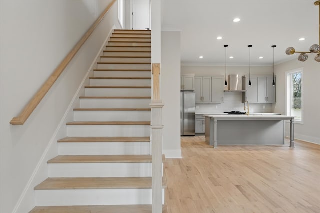 stairs with crown molding, recessed lighting, wood finished floors, and baseboards