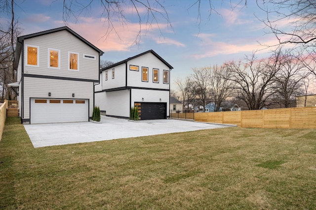 rear view of house with a yard, fence, a garage, and driveway