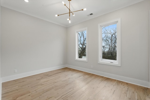 empty room with visible vents, baseboards, ornamental molding, light wood-style floors, and a notable chandelier