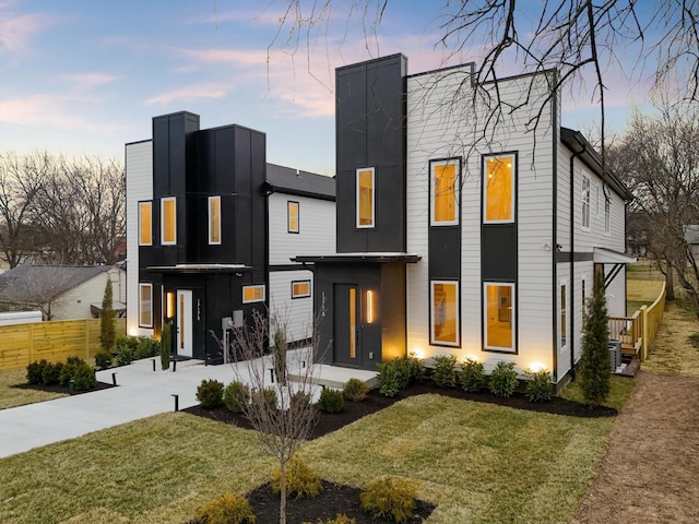 contemporary home featuring a yard and fence