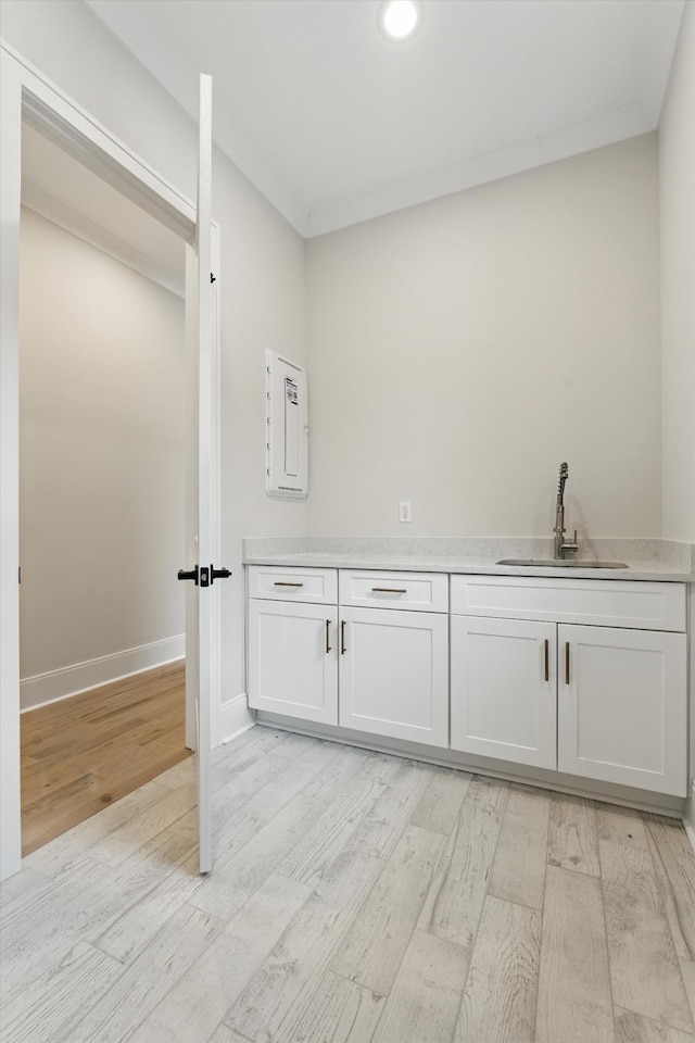 interior space featuring a sink, baseboards, and light wood-style flooring