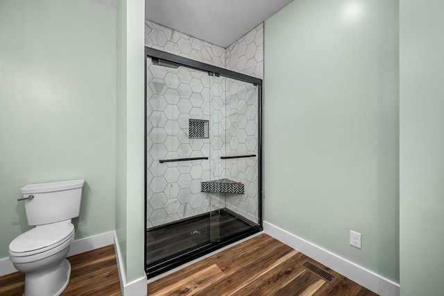 bathroom with toilet, hardwood / wood-style flooring, and a shower with door