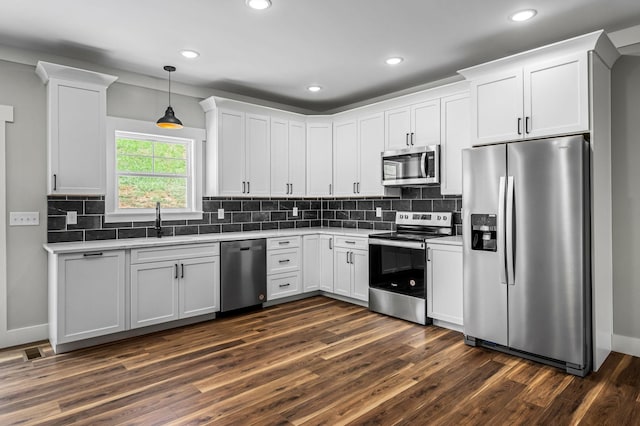 kitchen featuring appliances with stainless steel finishes, white cabinetry, dark hardwood / wood-style flooring, sink, and hanging light fixtures