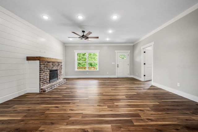 unfurnished living room featuring ceiling fan, a brick fireplace, crown molding, and dark hardwood / wood-style floors