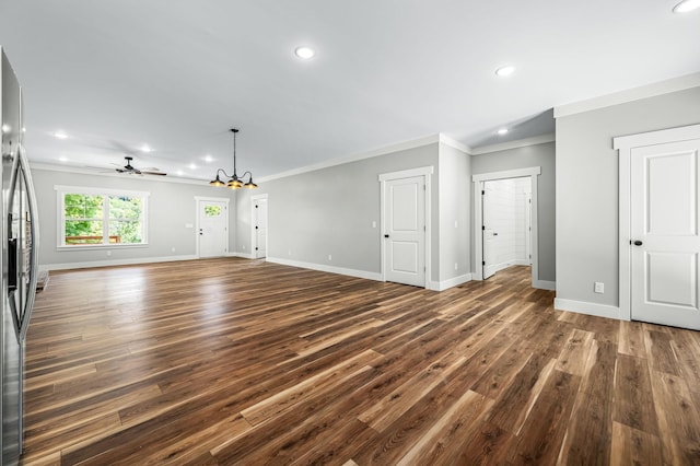 unfurnished living room featuring ceiling fan with notable chandelier, dark hardwood / wood-style flooring, and crown molding