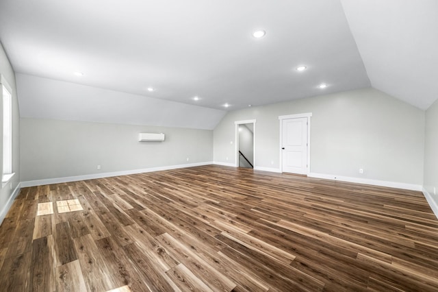 additional living space with lofted ceiling, a wall mounted AC, and dark wood-type flooring