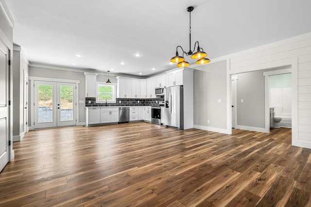 kitchen with decorative light fixtures, decorative backsplash, an inviting chandelier, white cabinetry, and appliances with stainless steel finishes