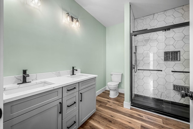 bathroom featuring toilet, vanity, wood-type flooring, and a shower with shower door