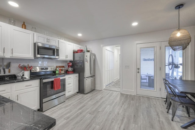 kitchen featuring light wood-type flooring, backsplash, appliances with stainless steel finishes, and white cabinetry