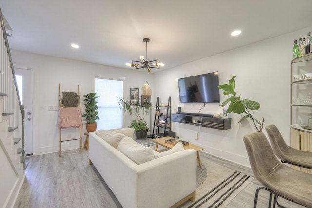 living room featuring a wealth of natural light, a chandelier, and light wood-type flooring