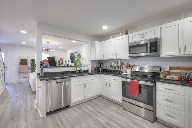 kitchen featuring white cabinetry, appliances with stainless steel finishes, a chandelier, light hardwood / wood-style flooring, and sink