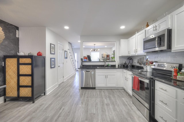 kitchen featuring appliances with stainless steel finishes, white cabinets, and decorative light fixtures