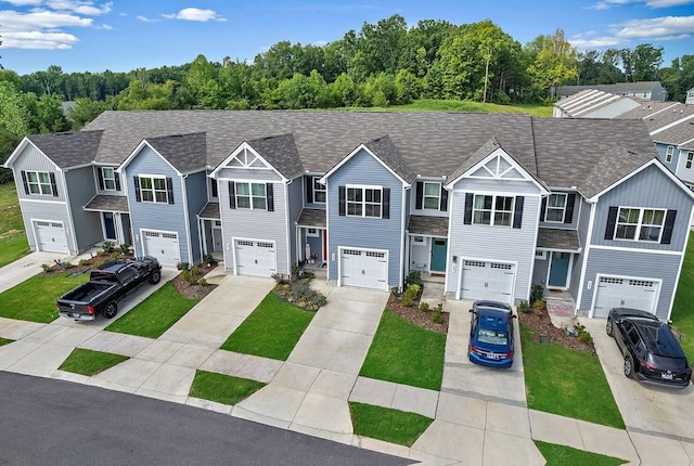 multi unit property with driveway, roof with shingles, and an attached garage