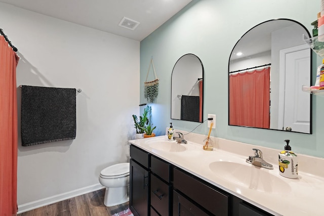 full bathroom with visible vents, a sink, toilet, and wood finished floors