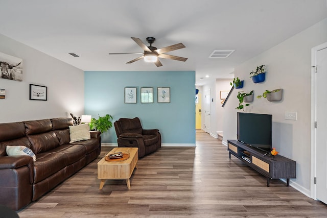 living area featuring visible vents, ceiling fan, baseboards, and wood finished floors