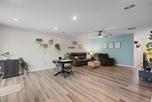 living room featuring baseboards, visible vents, and light wood finished floors